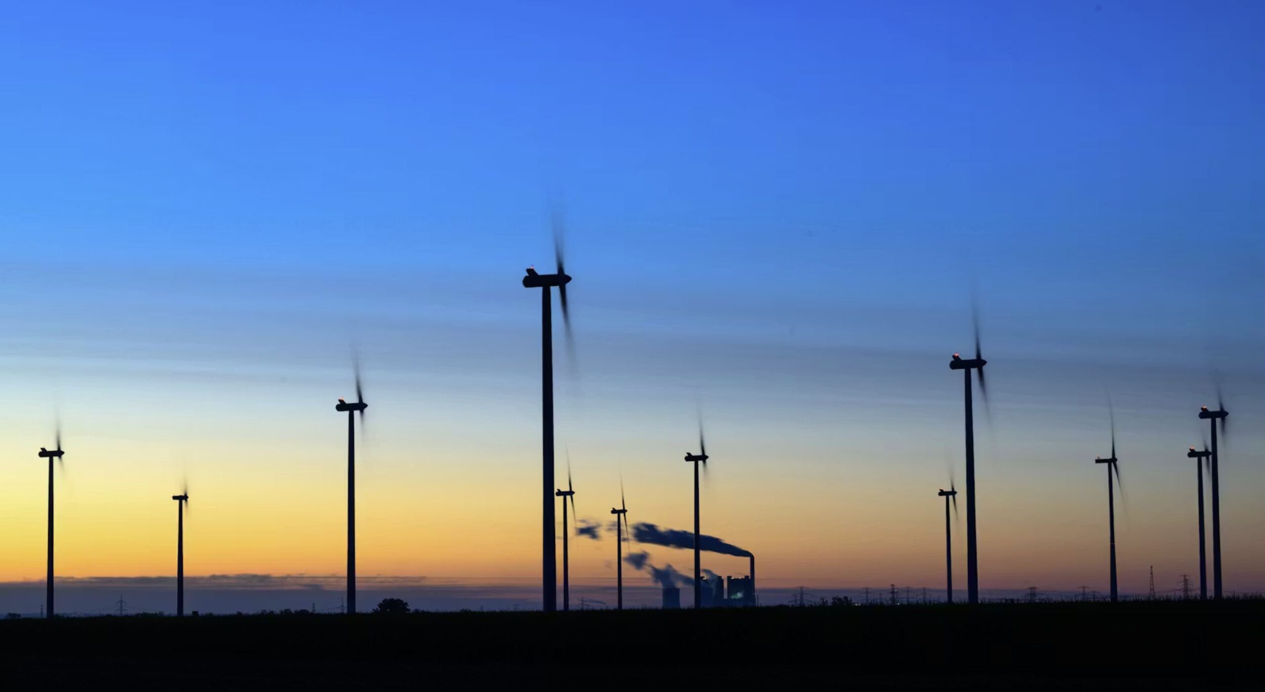Windräder drehen sich vor der Kulisse des Braunkohlekraftwerks Schkopau, Sachsen-Anhalt.