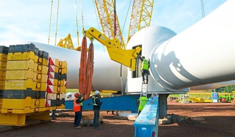 Die Windradnabe mit den drei Rotorblättern wiegt fast 102 Tonnen. Arbeiter schrauben eine Halterung (gelb) an, an der ein Kran den Rotor in die Höhe ziehen wird.