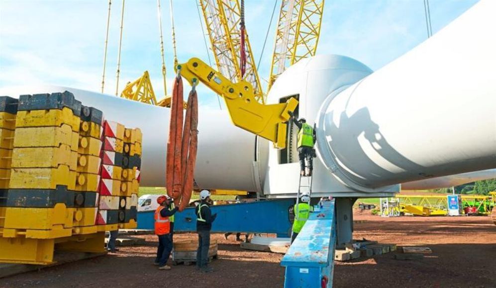 Die Windradnabe mit den drei Rotorblättern wiegt fast 102 Tonnen. Arbeiter schrauben eine Halterung (gelb) an, an der ein Kran den Rotor in die Höhe ziehen wird.